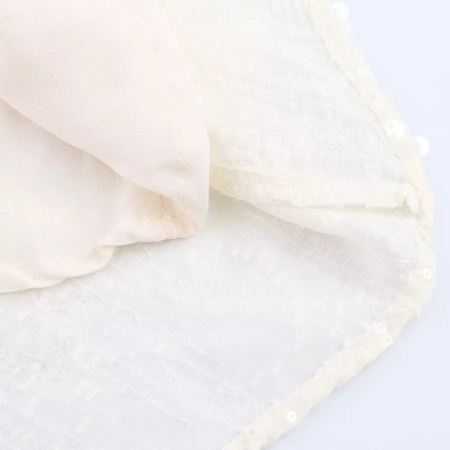 Close-up of the inner lining and finished hem on the cream sequined mesh dress