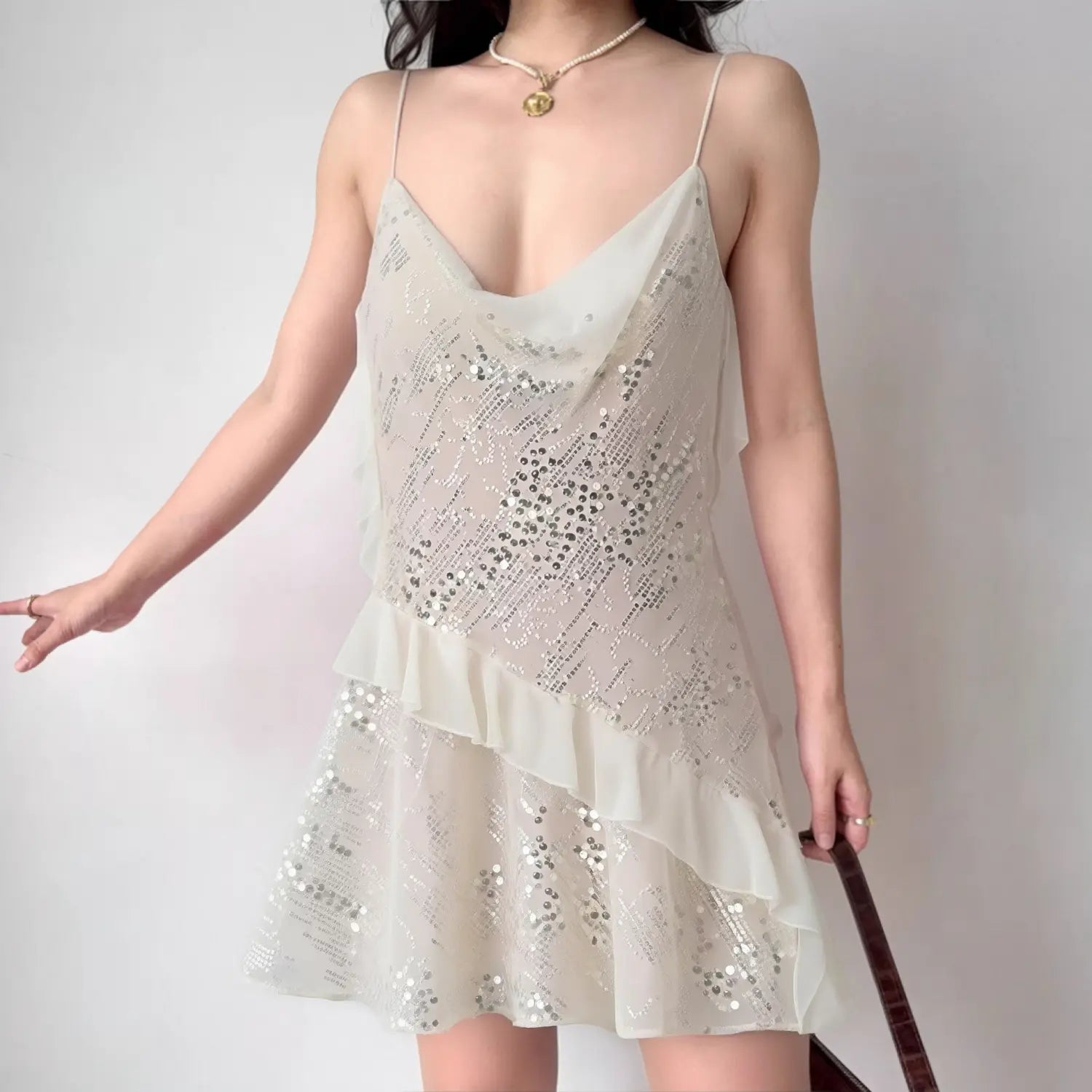 Lifestyle shot of model wearing the cream sequined slip dress, showing the cowl neck, ruffled skirt, and full silhouette
