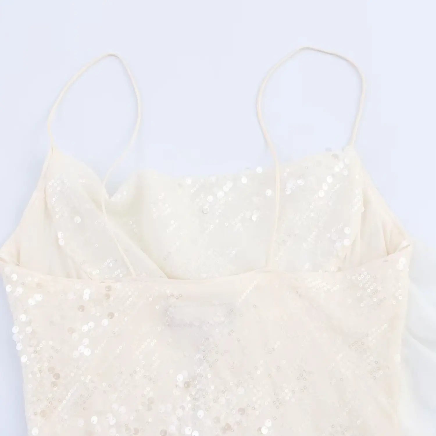 Close-up of the cowl neckline and thin spaghetti straps on the cream sequined mesh dress