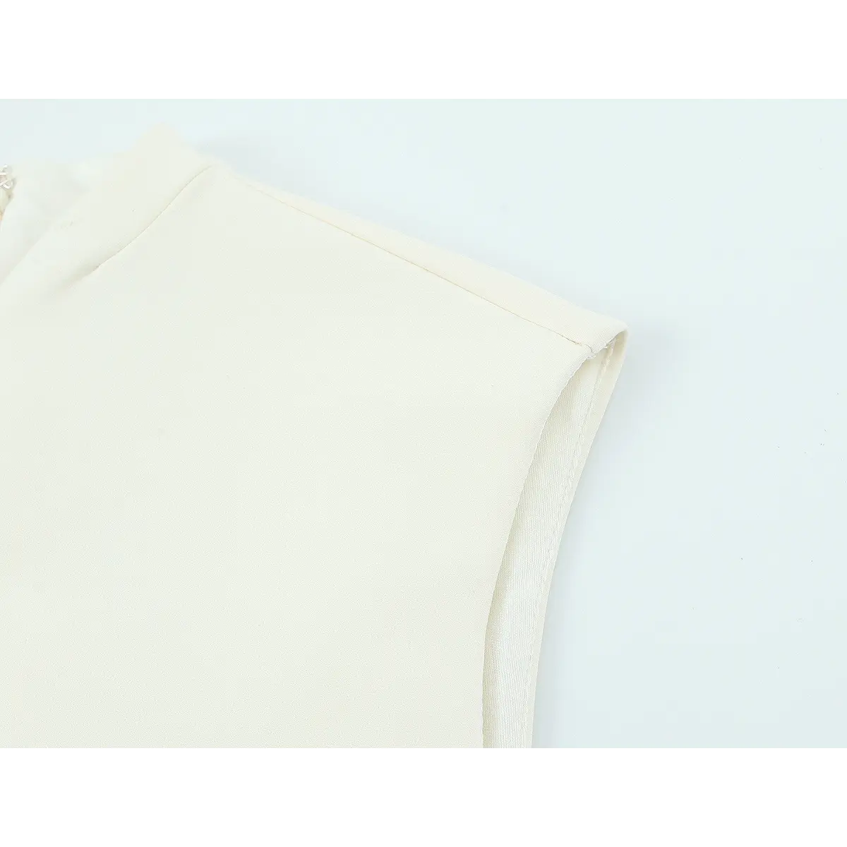 Armhole and shoulder detail of cream sleeveless dress, showing the clean stitching and lining
