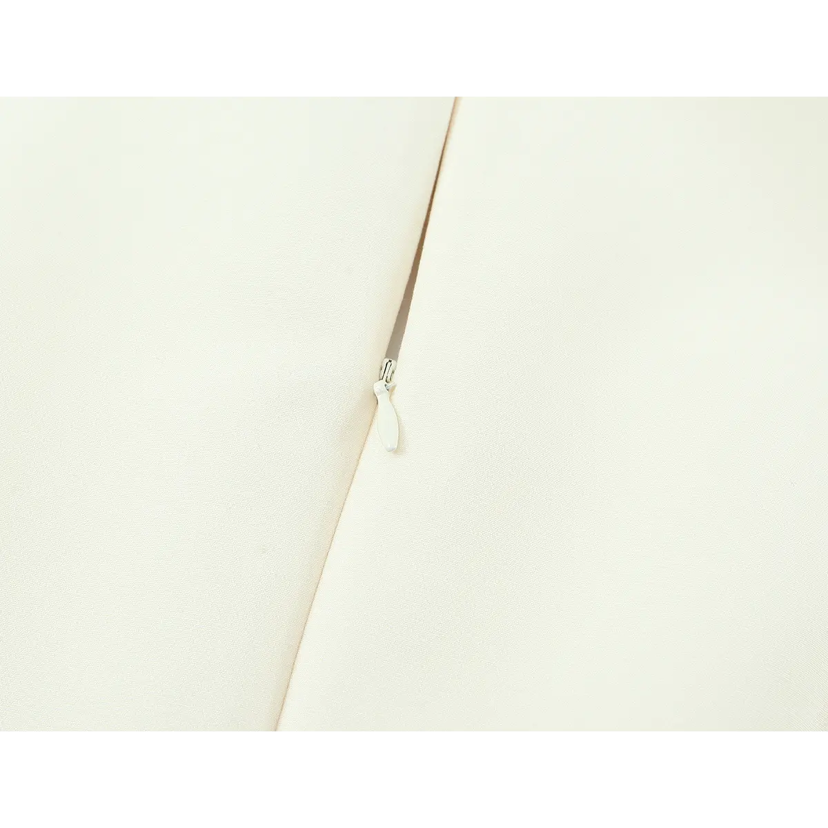 Close-up of the side zipper pull on the cream sleeveless dress
