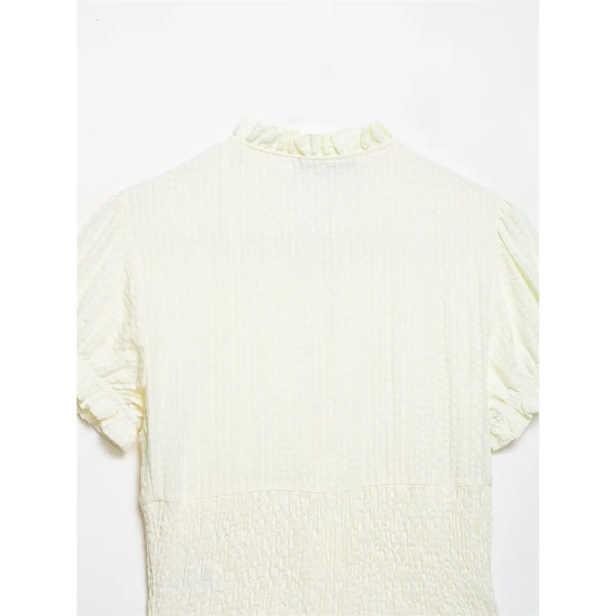 Back view of cream textured blouse, showing the ruffled collar and smocked waist