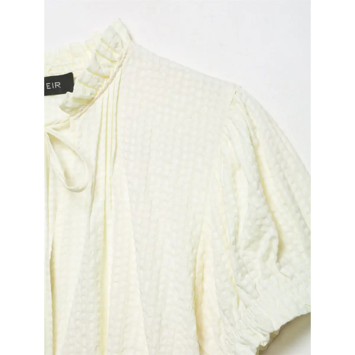 Close-up of the blouse's shoulder, showing the textured fabric and gathered puff sleeve design