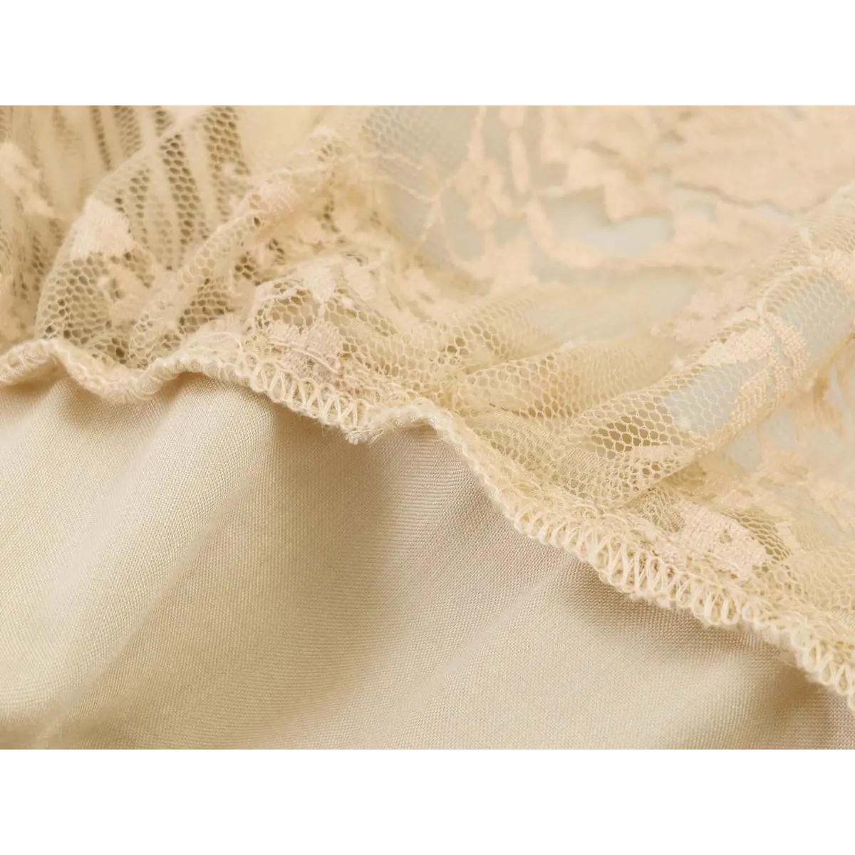 Close-up of the delicate lace texture and scalloped edge on the cream cami top