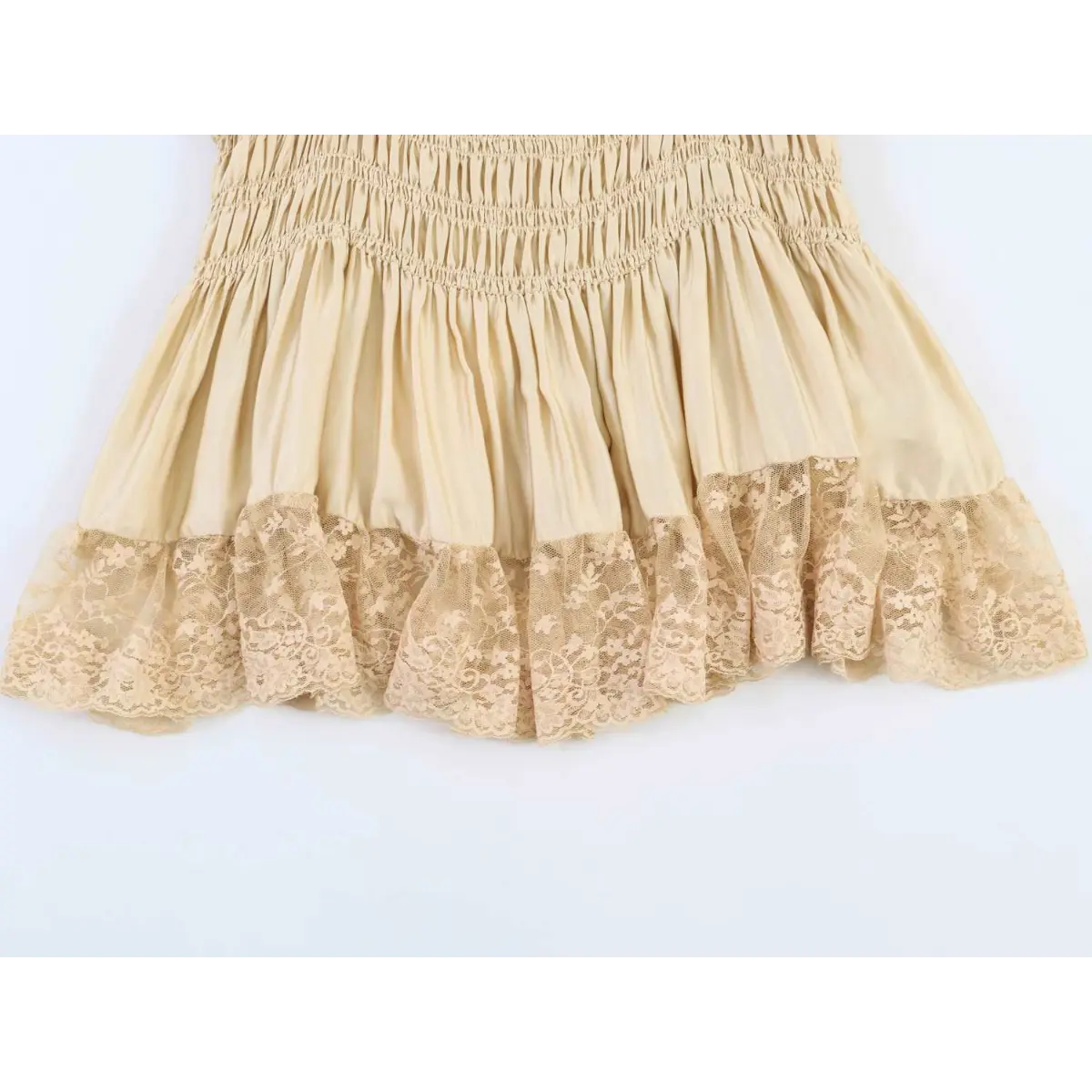 Close-up of the lace-trimmed ruffled hem on the cream smocked cami top