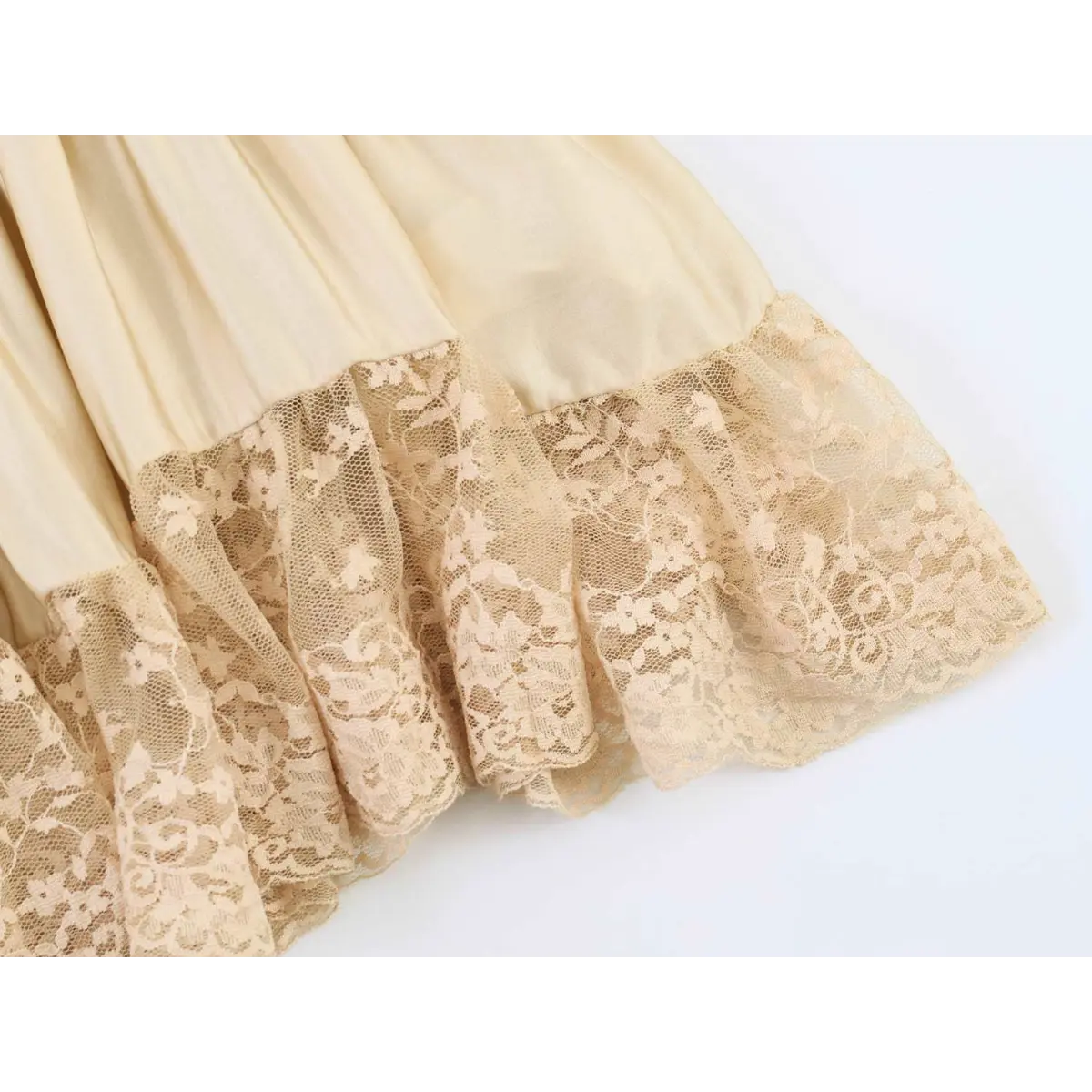 Close-up of the layered construction and lace trim on the cream smocked cami top