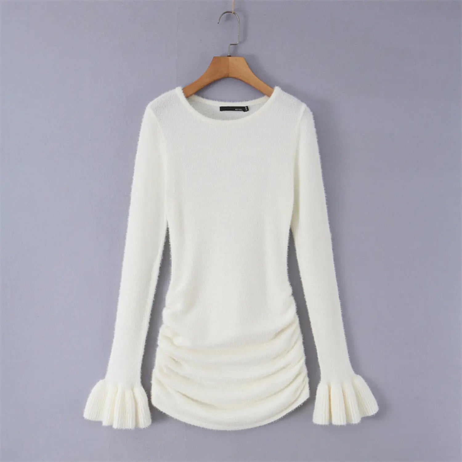 Hanging product photo cream fuzzy plush knit top on wooden hanger, round neck ruched waist ribbed flared bell cuffs long sleeve