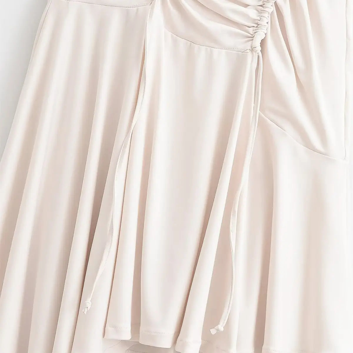 Close-up of the flared mermaid hem and drawstring ends on the cream maxi dress