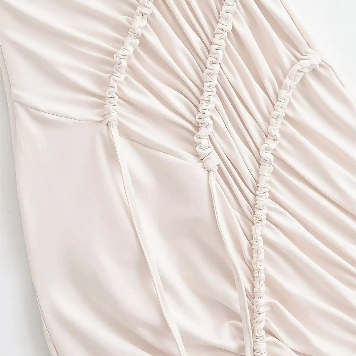 Close-up of the diagonal drawstring ruching on the cream maxi dress, showing the gathered fabric and adjustable drawstrings