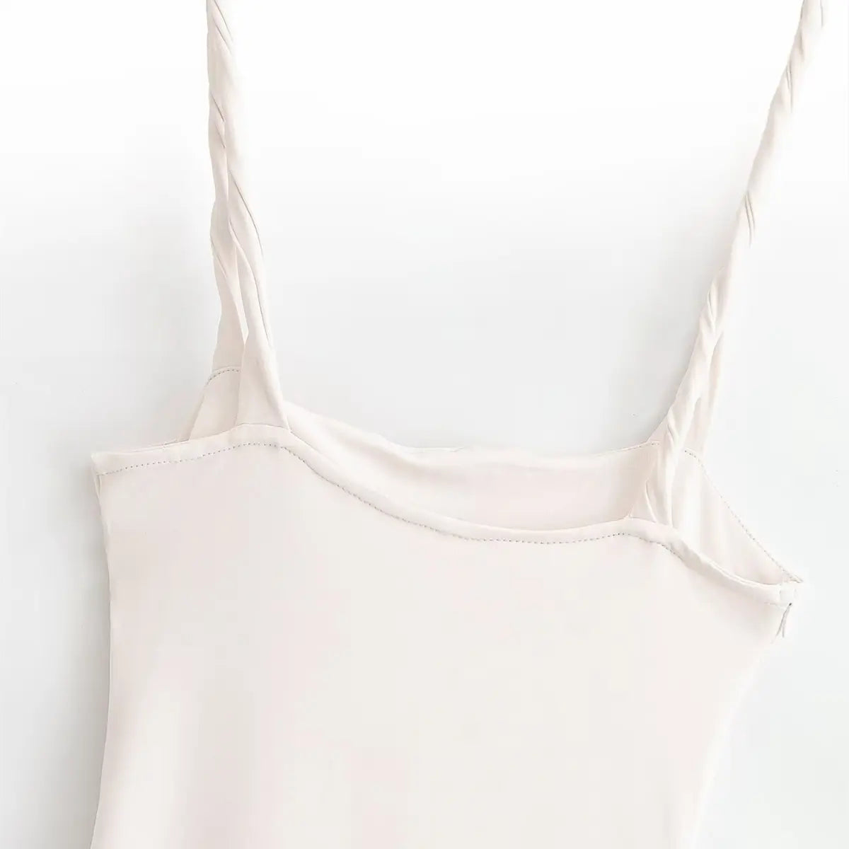 Close-up of the twisted spaghetti strap and back neckline on the cream maxi dress