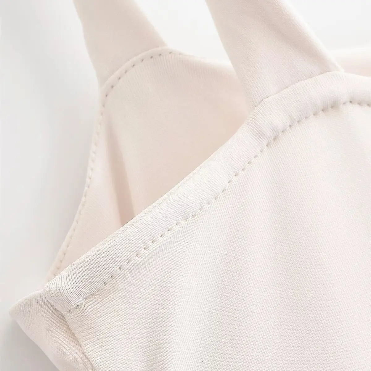 Close-up of the strap and neckline seam on the cream maxi dress, showing the neat stitching