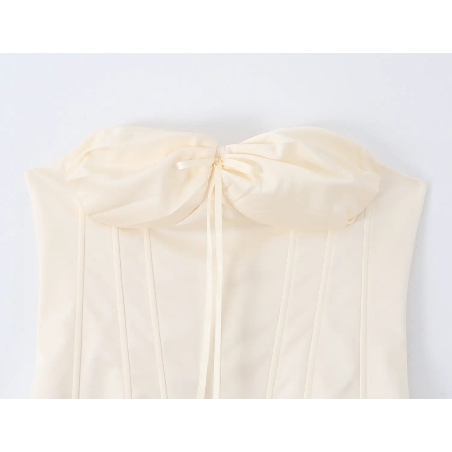 Close‑up of cream strapless corset top, large front bow detail with satin ribbon tie, boned stitching on bodice