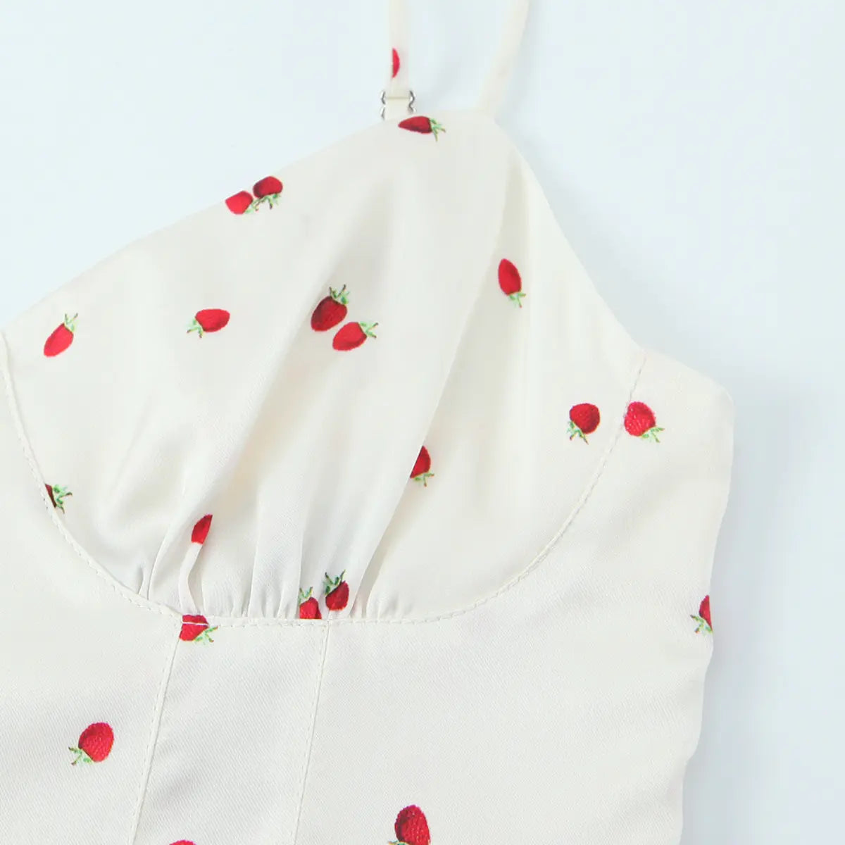 Close-up of the bust area on the cream cami top, showing the gathered sweetheart neckline and strawberry print