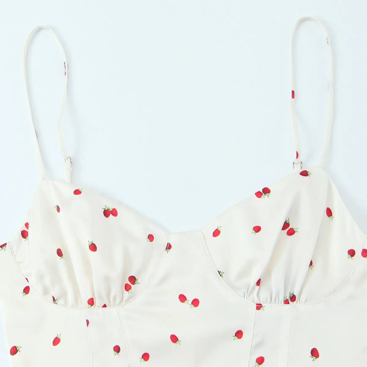 Front view of the cream cami top with strawberry print, featuring adjustable straps, sweetheart neckline, and gathered bust cups