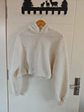 Cream teddy fleece hooded cropped sweatshirt hanging on door, front view