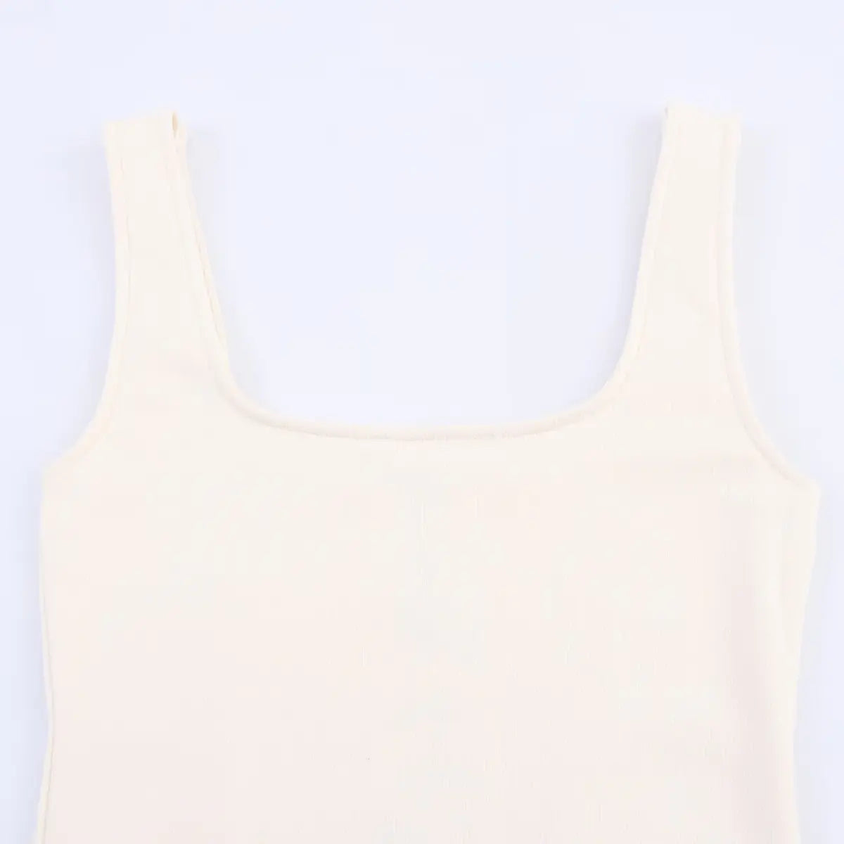 Close-up of the square neckline and ribbed knit bodice on the cream dress