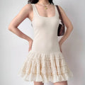Lifestyle shot of model wearing cream square-neck tiered ruffle mini dress, showing full silhouette and tiered skirt