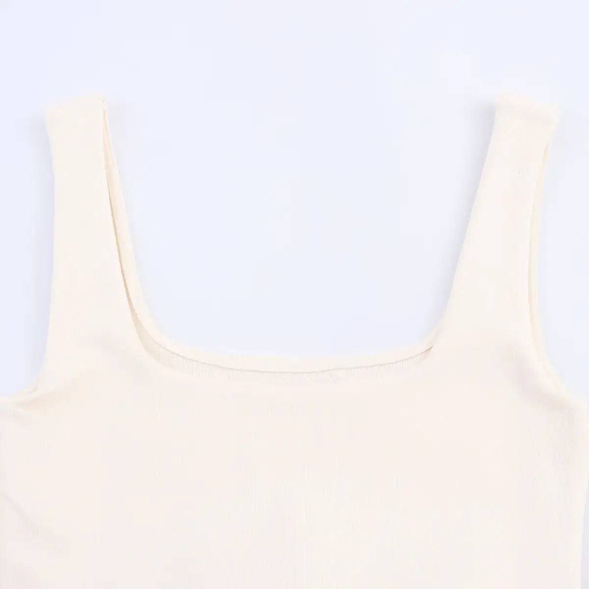 Close-up of the wide square neckline on the cream ribbed knit dress