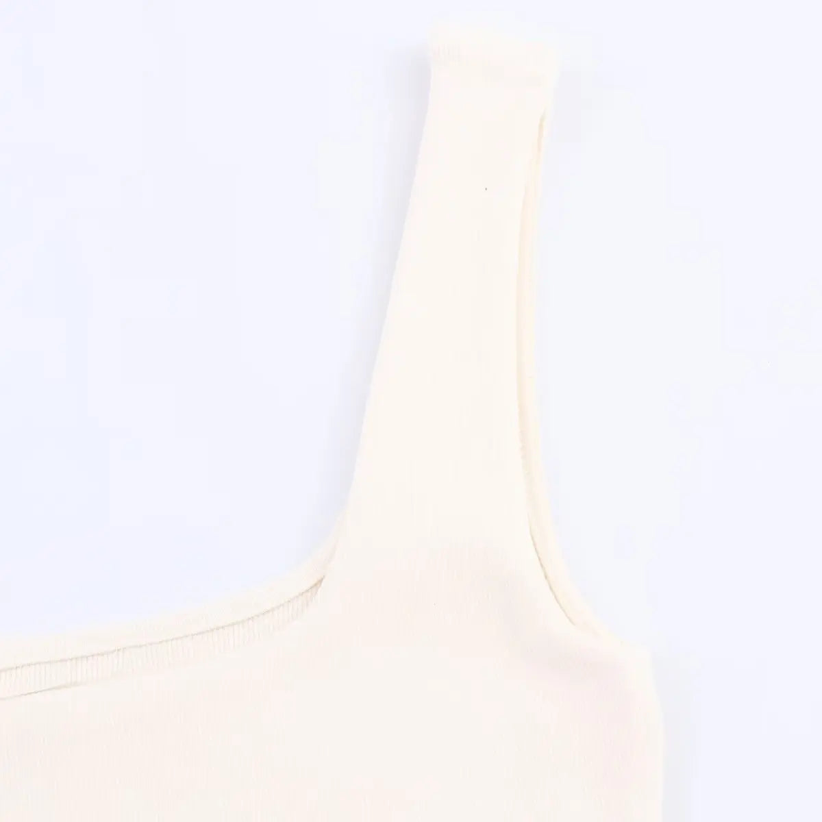Close-up of the wide ribbed shoulder strap on the cream knit dress