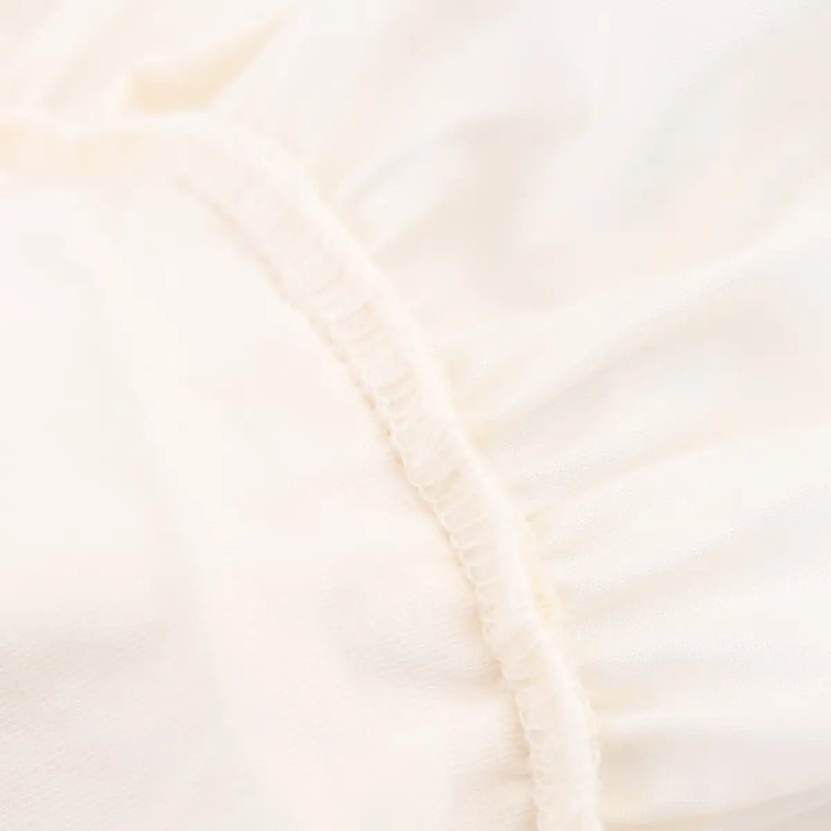 Close-up of the elasticated waist seam where the ribbed knit bodice meets the ruffled skirt