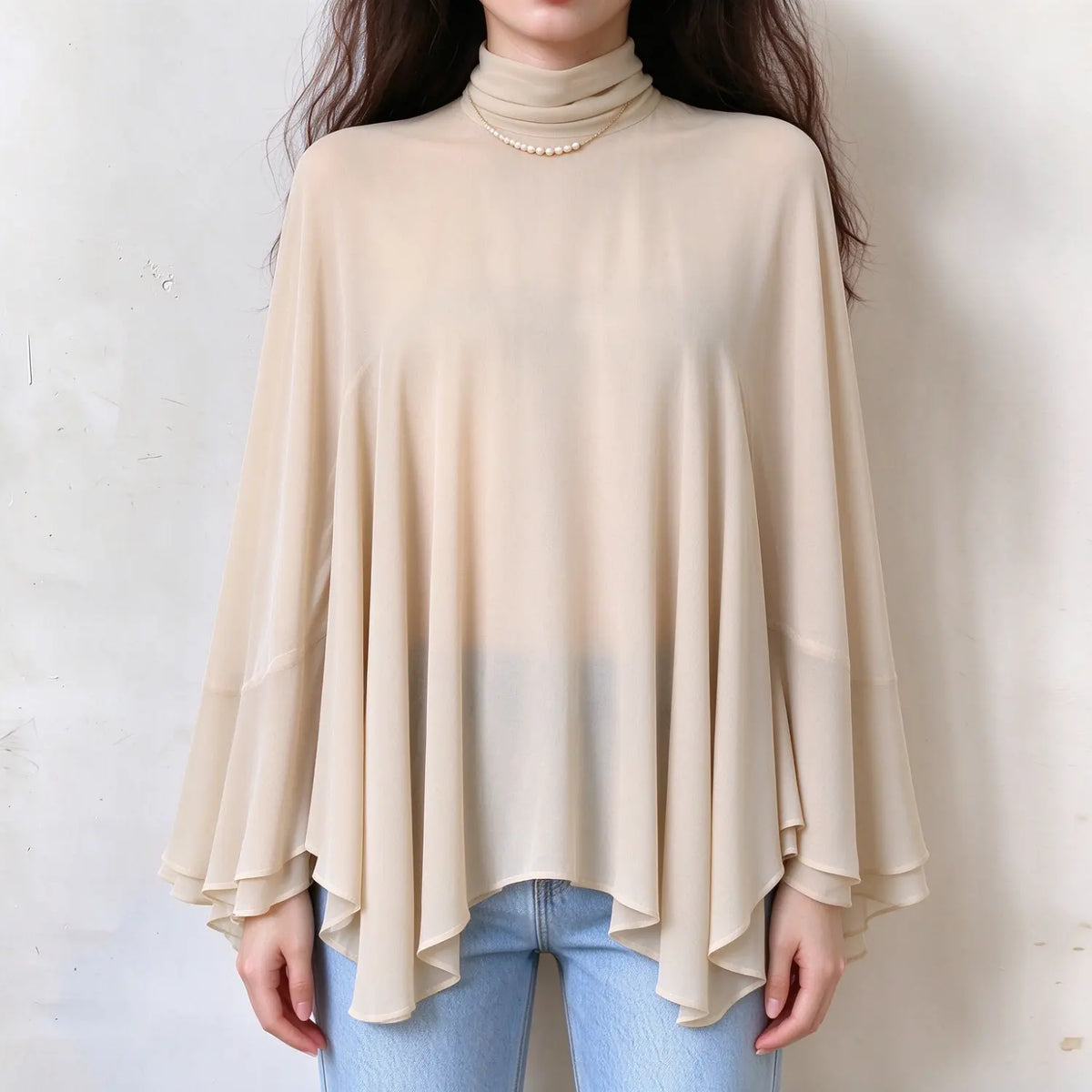 Model wearing cream turtleneck bell sleeve cape blouse, front view