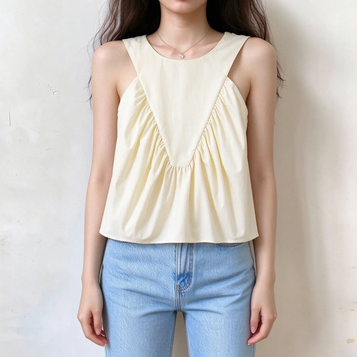 Model wearing cream v shape ruched sleeveless crop top, front view