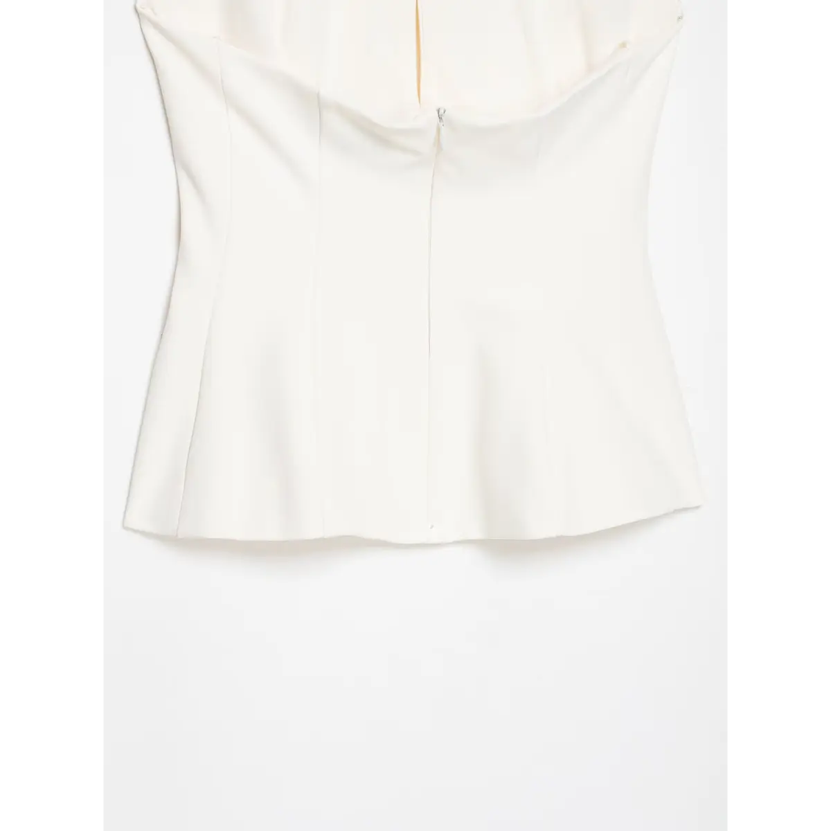Close-up of the center back zipper closure on a cream-white halter top.
