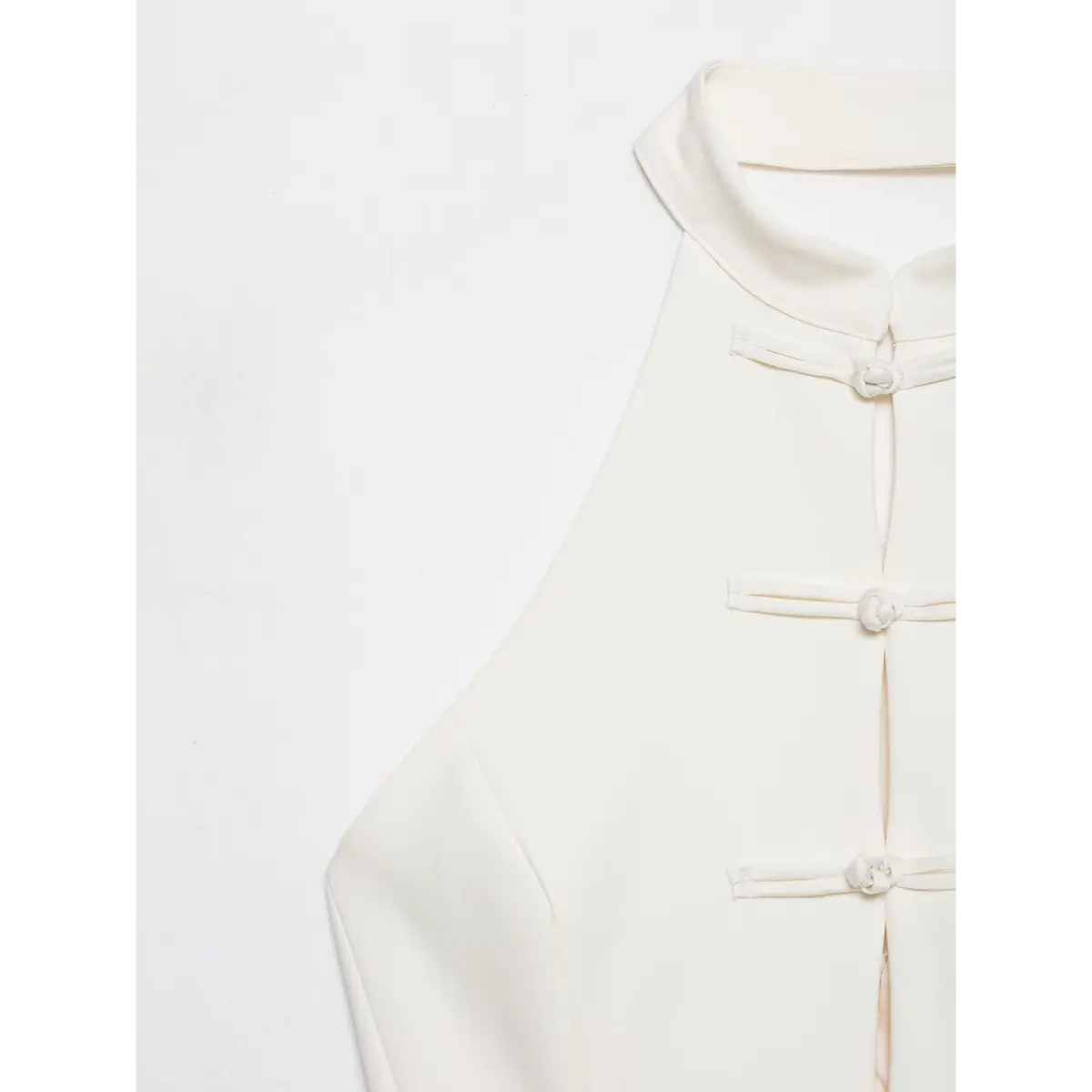 Close-up of the high neck and traditional Chinese knot buttons on a cream-white halter top.