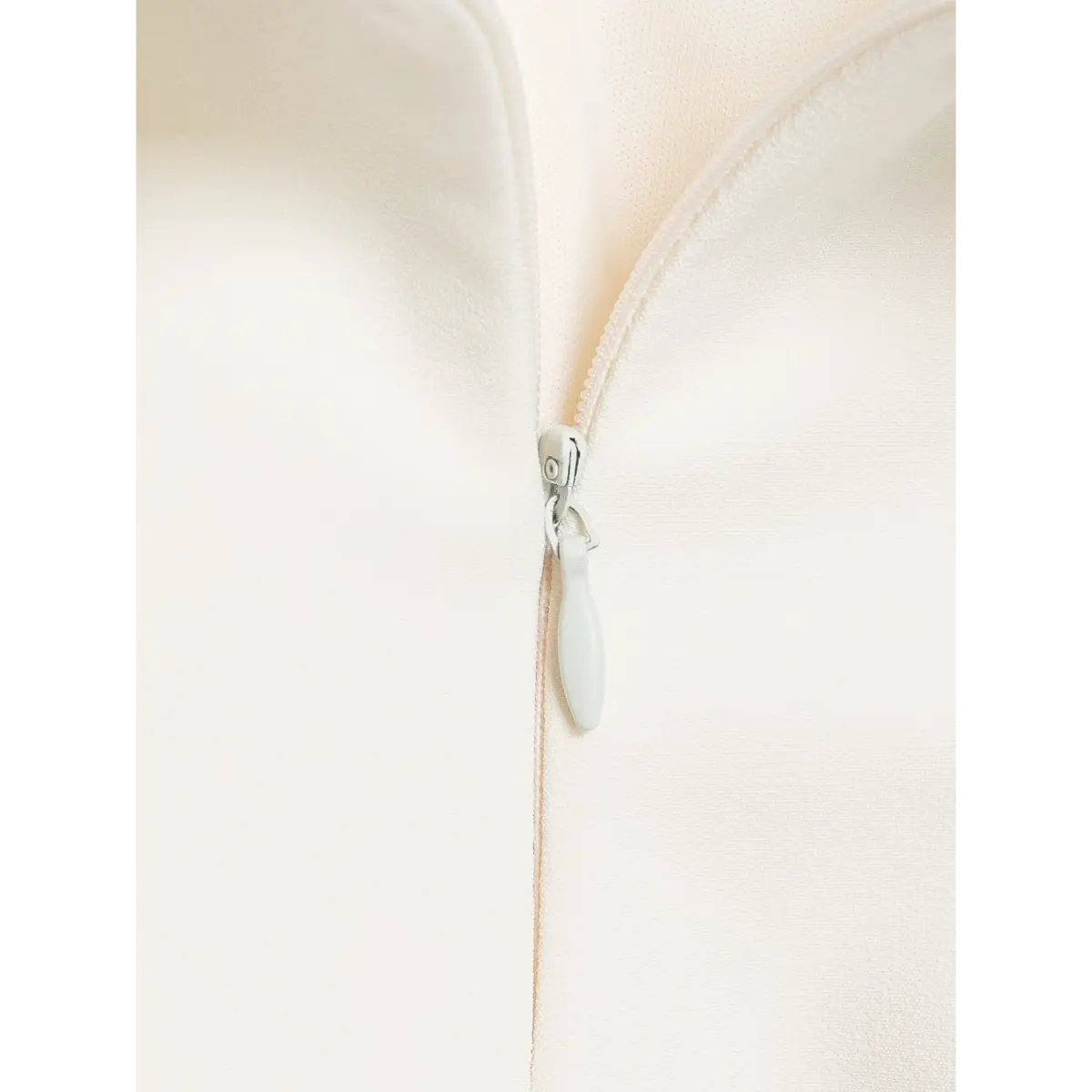  Close-up of the zipper pull on a cream-white halter top.