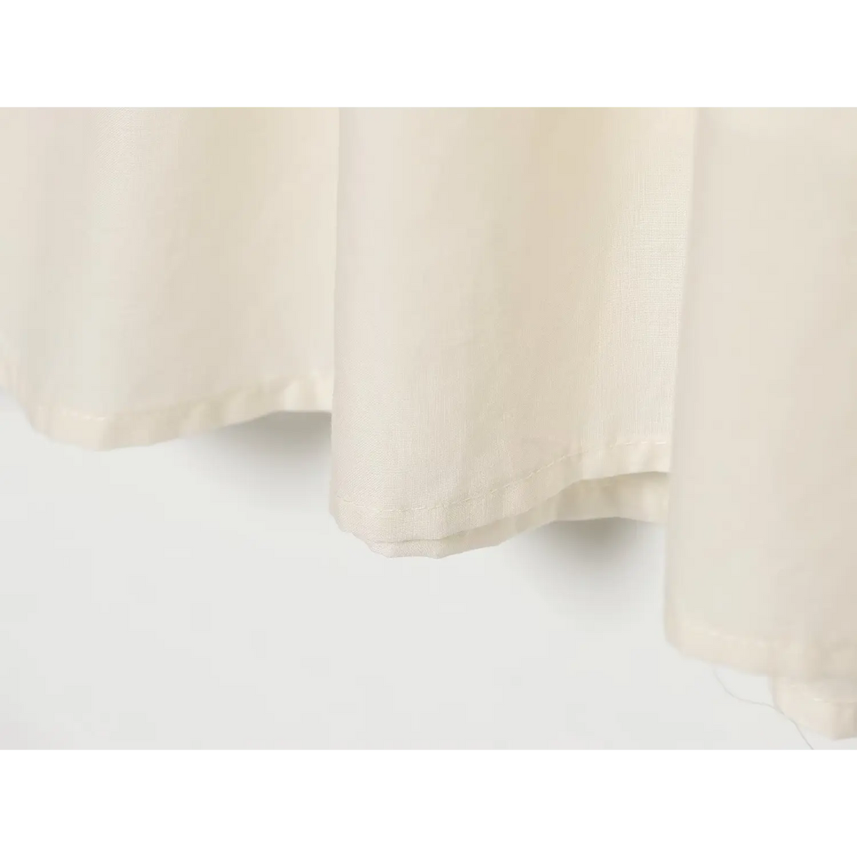 Close-up of neat hem stitching on cream white relaxed midi dress