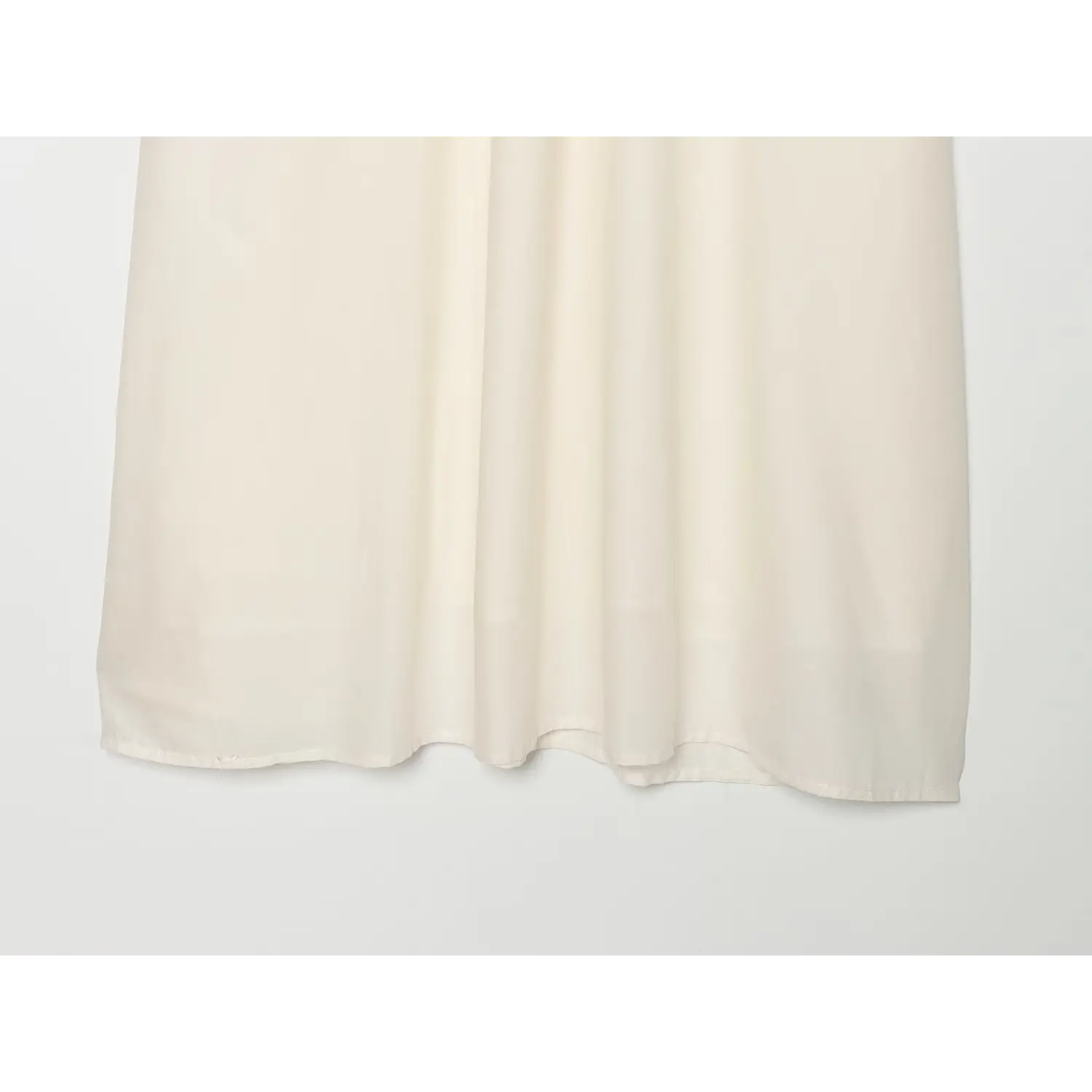 Close-up of flowy skirt drape and soft creases on cream white midi dress