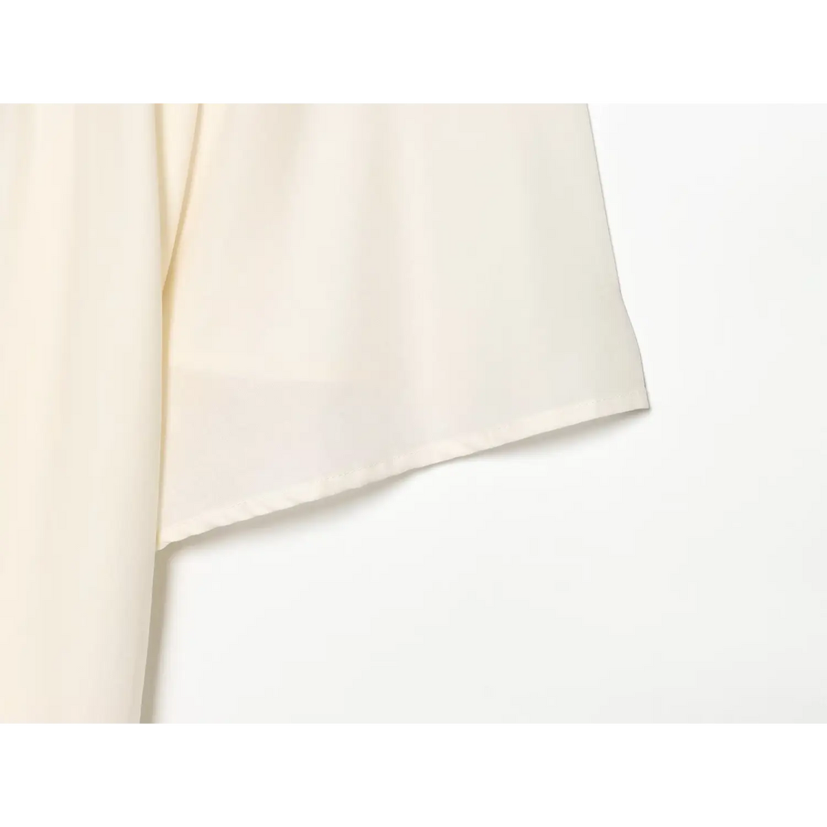 Close-up of soft cream white fabric and batwing sleeve edge on midi dress