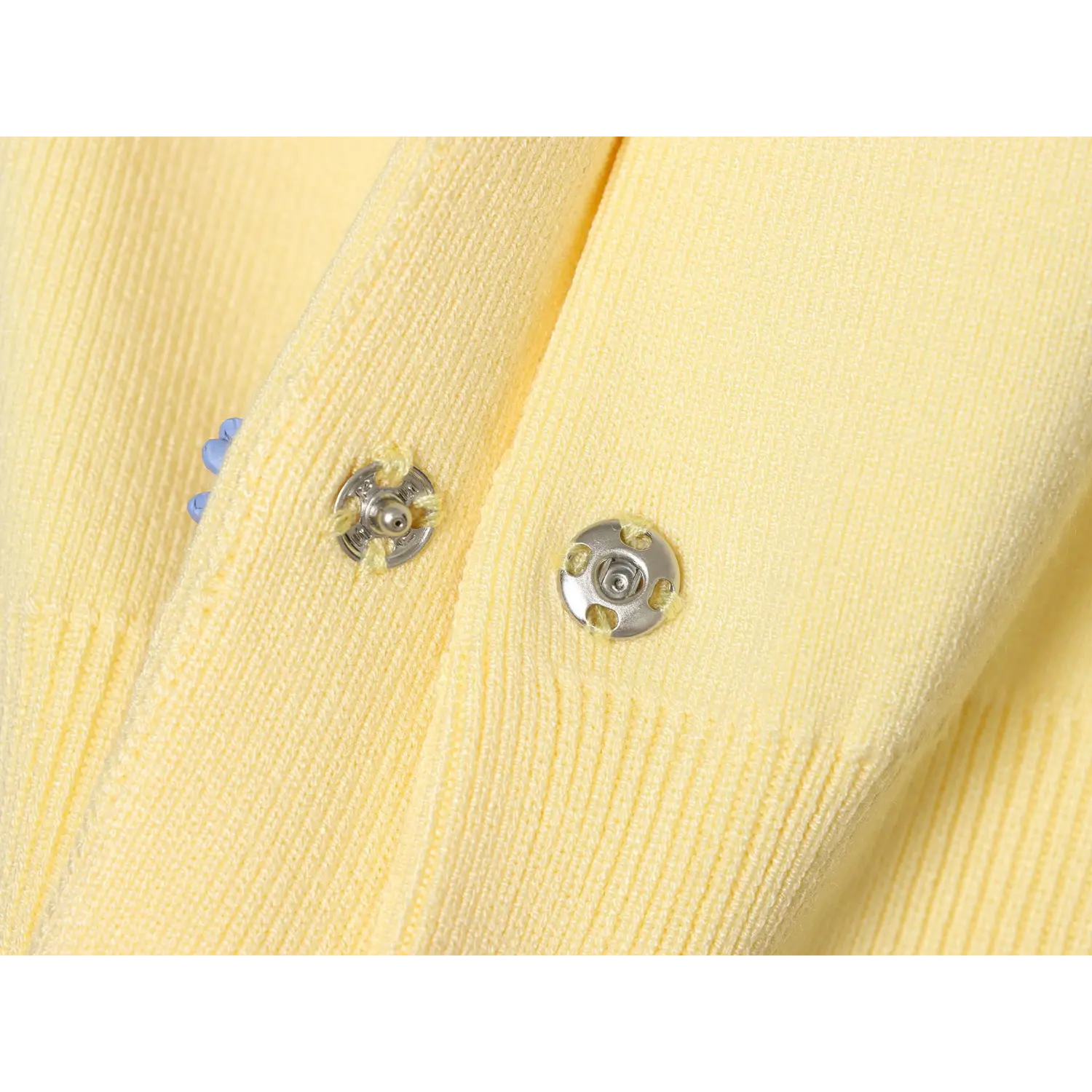 Inside placket metal snap fastener closeup, yellow thread stitching around metal snap, double layer knit binding edge