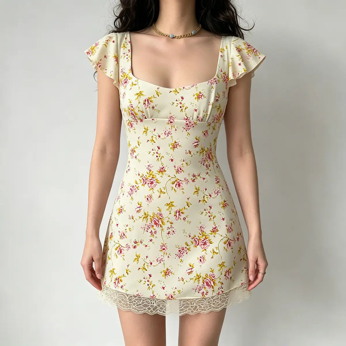Full front view of a model wearing a cream floral mini dress, showing the square neckline and fitted silhouette.
