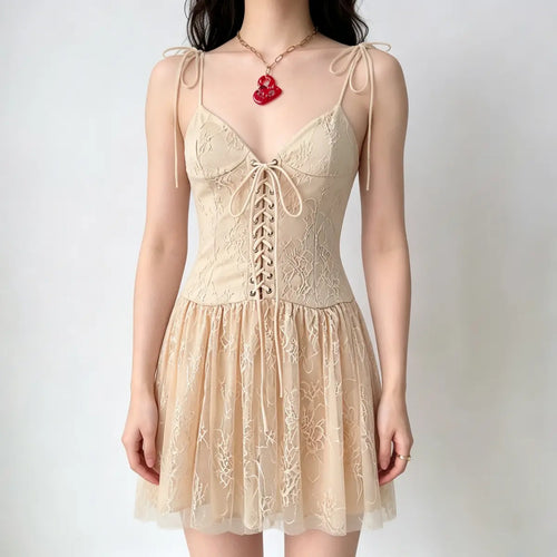 Model wearing a cream corset-style mini dress with a yellow and red floral print, tiered ruffled skirt, and thin tie straps, carrying a brown handbag.