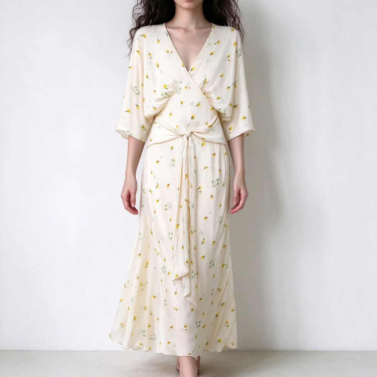 Model wearing cream yellow floral wrap maxi dress, v neck, elbow flutter sleeves, waist tie knot, lightweight flowy fabric with dandelion floral print