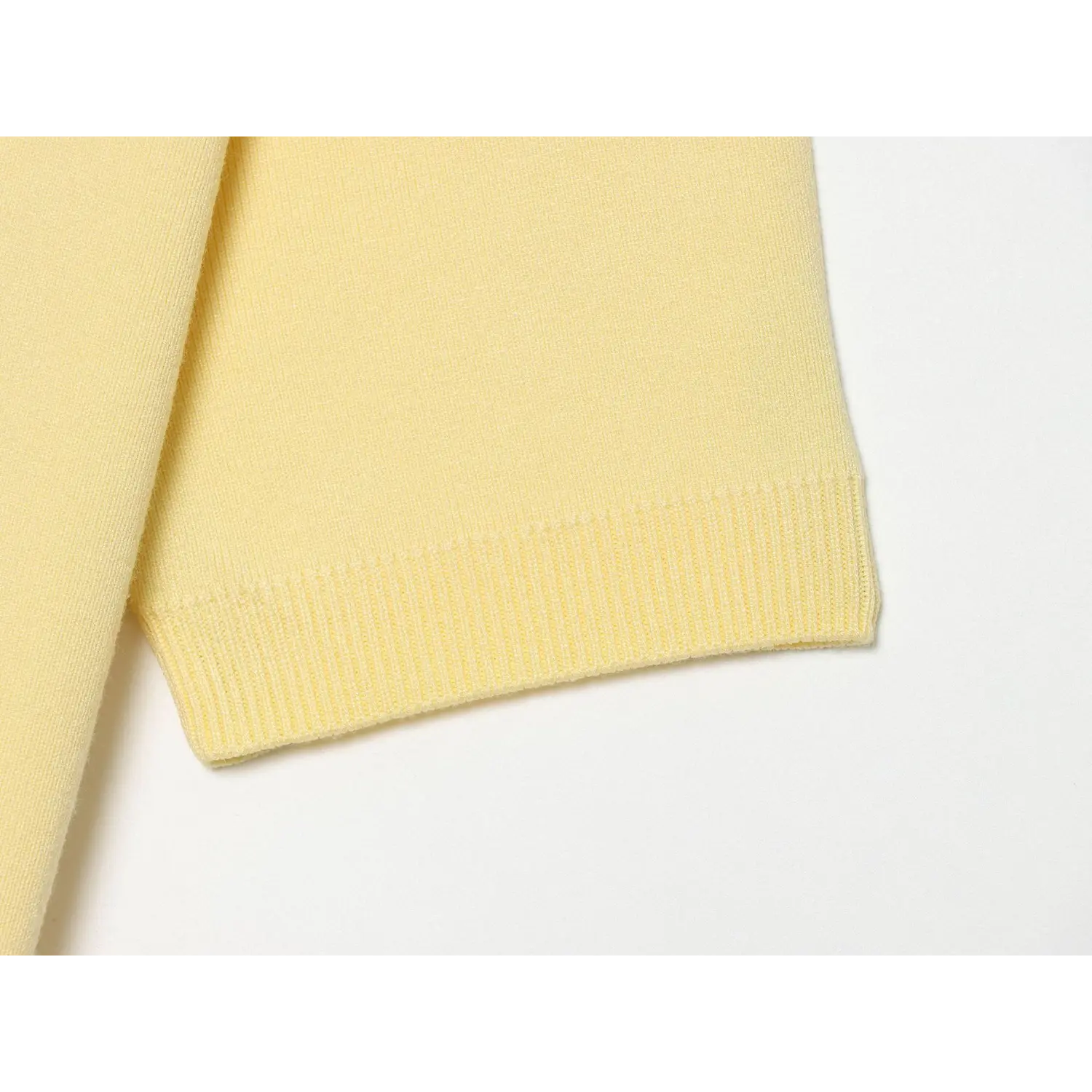 Bottom waist rib knit hem close-up, solid matching yellow rib binding, fine knit panel above rib band