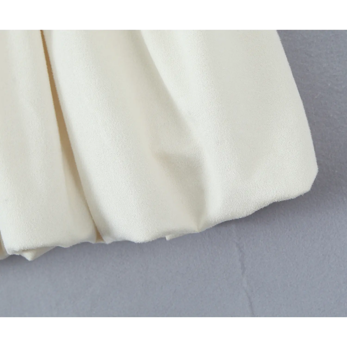 Close‑up of bubble skirt hem, cream soft fabric texture of polo mini dress