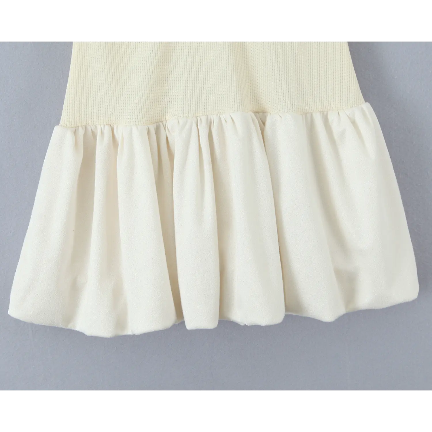 Close‑up view of gathered bubble ruffle skirt hem of cream polo mini dress