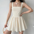 Model wearing cream corset camisole mini dress, full body front styling shot with woven handbag