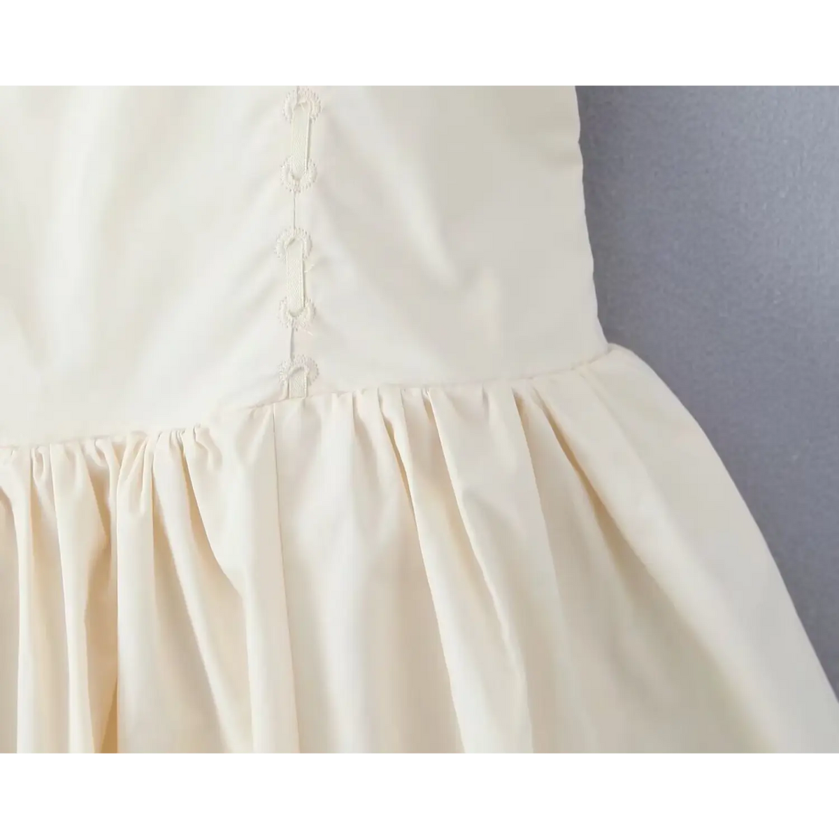 Close‑up of waist seam with vintage loop embroidery transition to gathered skirt