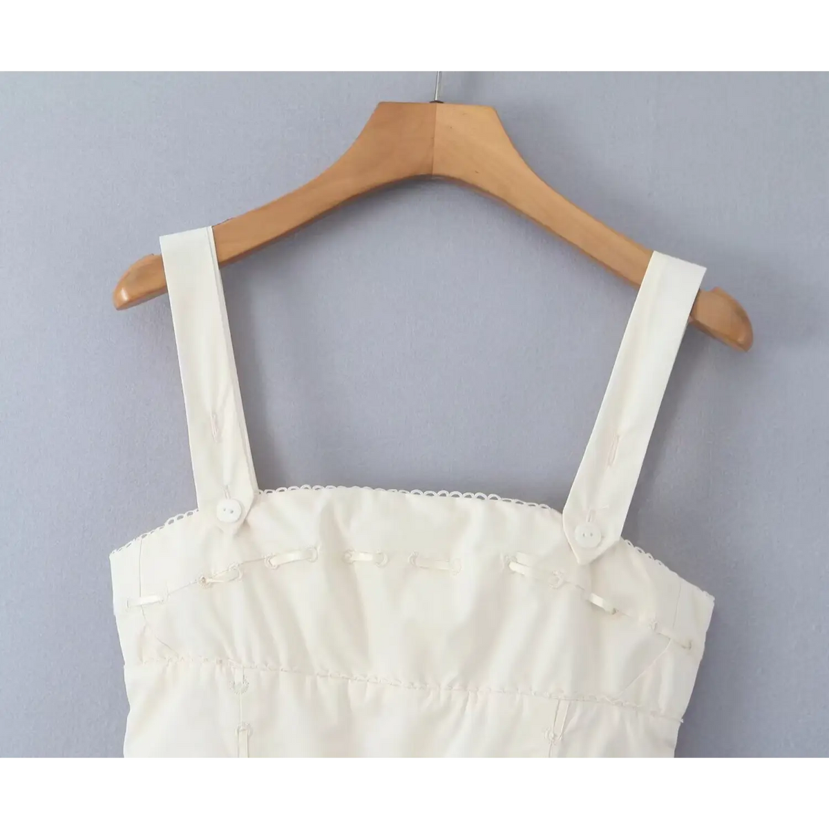 Close‑up of wide adjustable shoulder straps and embroidered bodice detail hanging on hanger