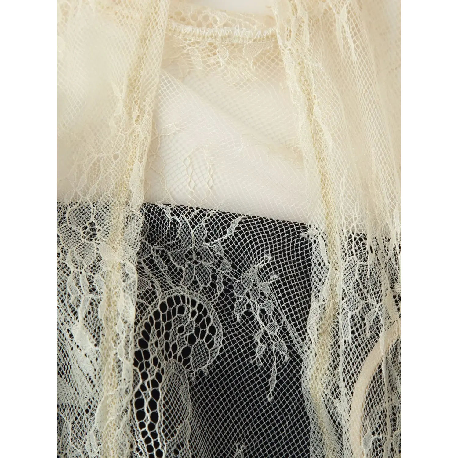 Macro view of cream floral lace bodice overlay layered over black satin slip mini dress