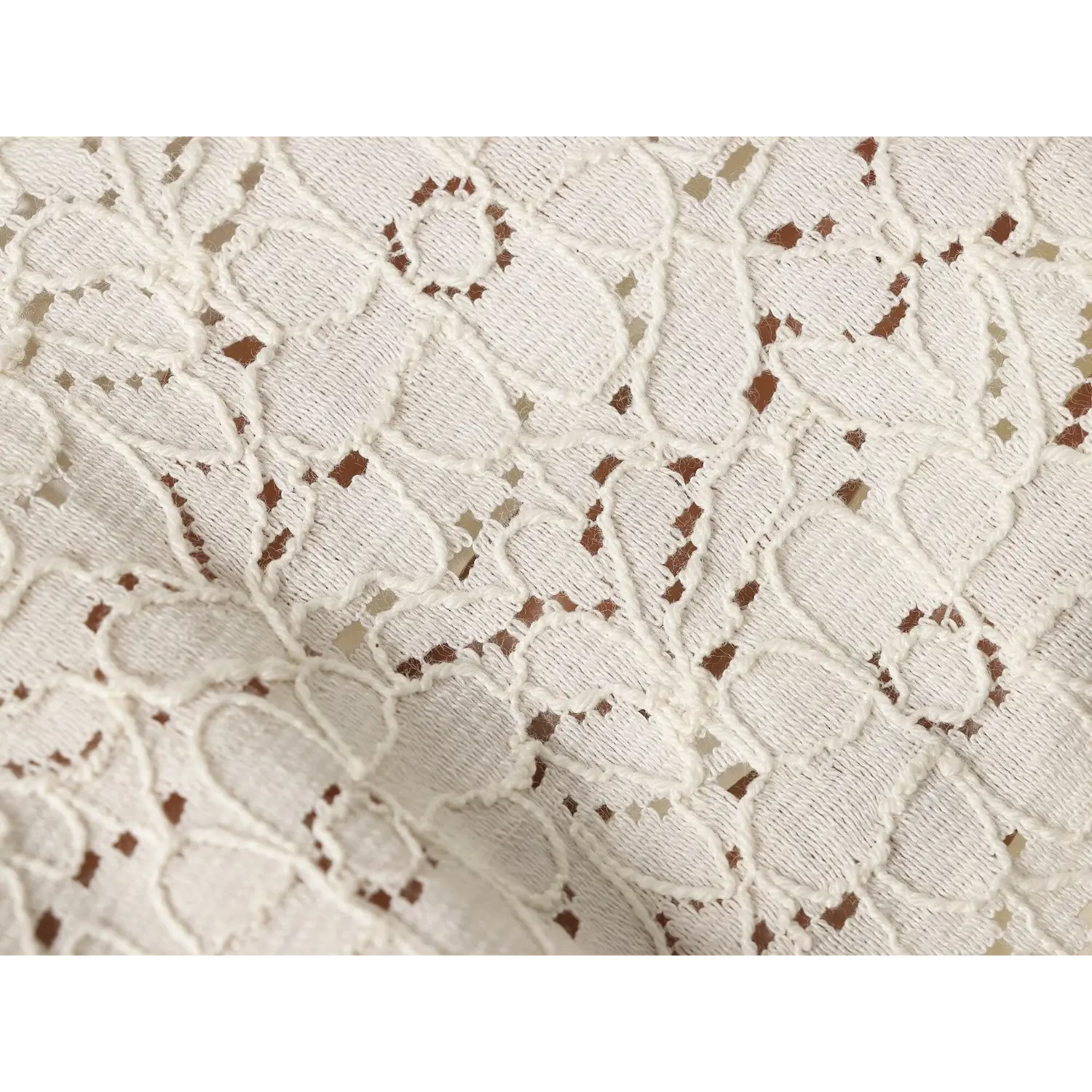 Extreme macro shot of cream floral lace fabric, showing hollow woven lace texture and floral motifs