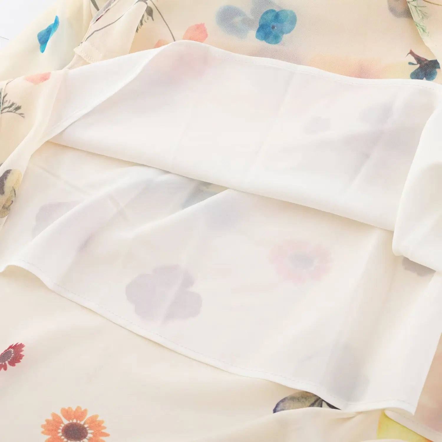Close‑up of double‑layer chiffon fabric on cream colorful floral maxi dress