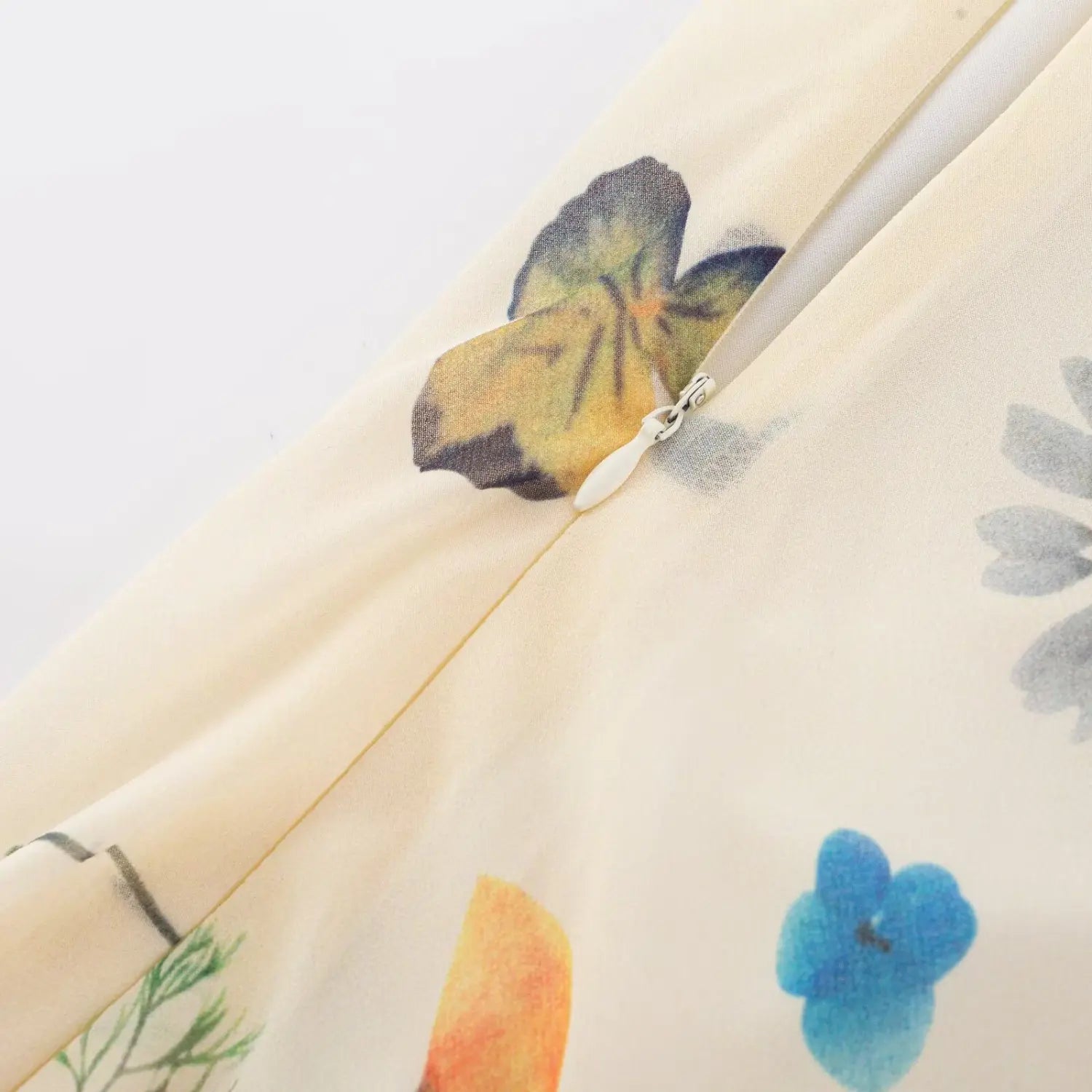 Partial close‑up of side zipper on cream colorful floral maxi dress