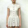 Model wearing cream lace mini dress, stand collar, cap sleeve, black button front, fit and flare short skirt