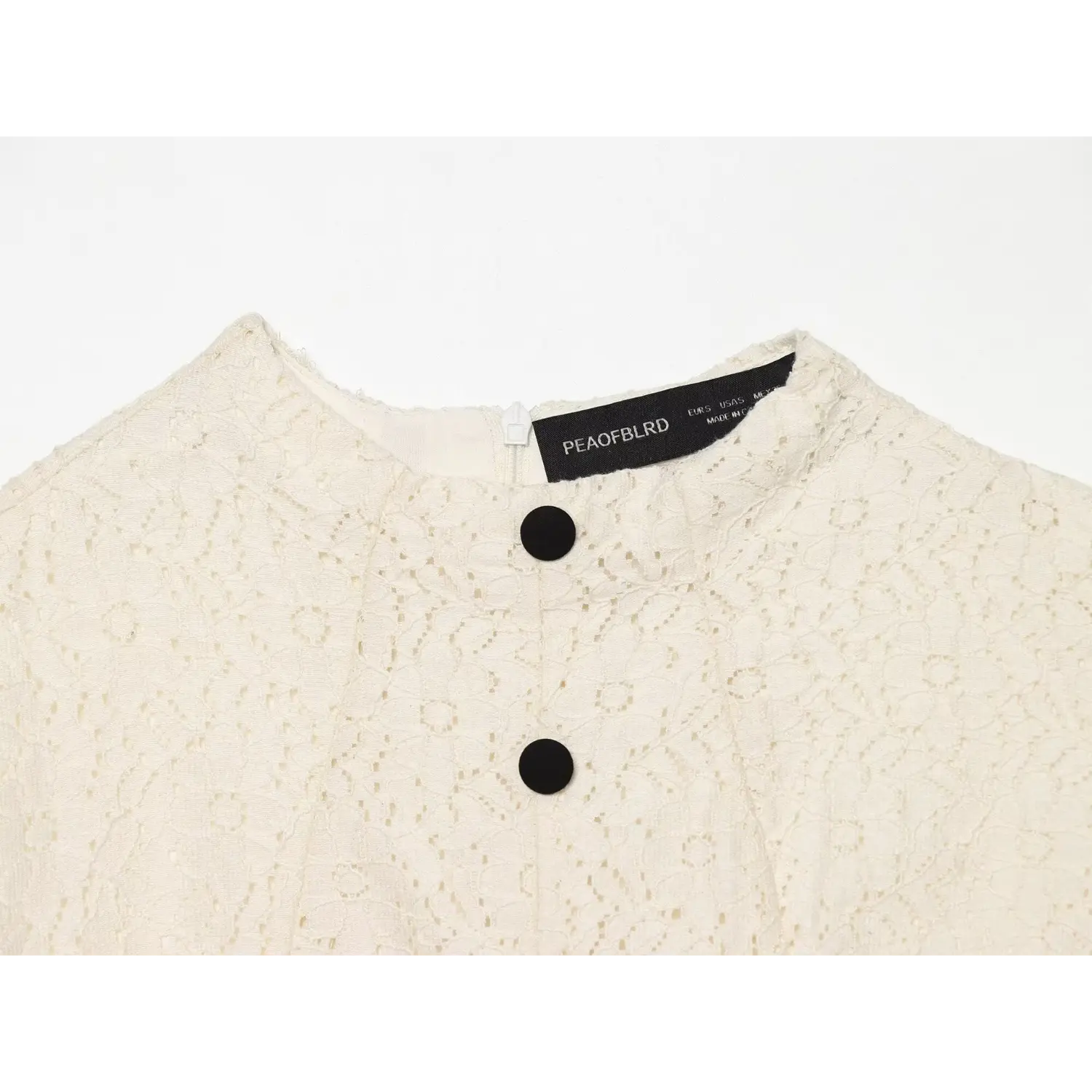 Macro close‑up of cream lace dress stand collar, inner brand label, top black button and back neck zipper detail