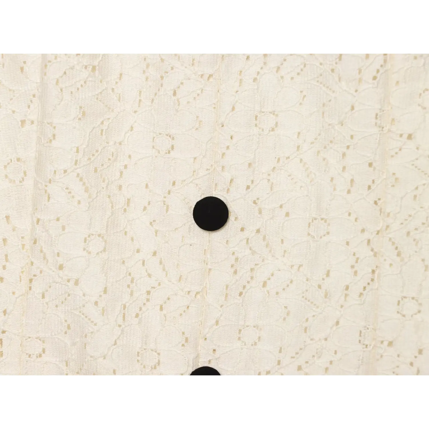 Macro detail of round black decorative button on cream floral lace dress front placket, lace pattern texture
