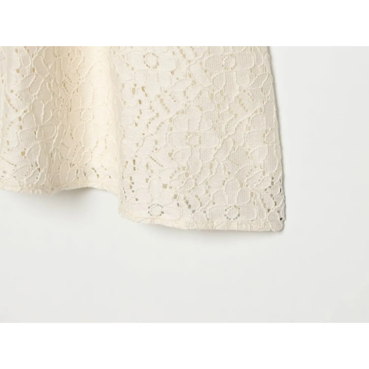 Macro close‑up of cream lace dress skirt hem, intricate floral lace edge finishing detail